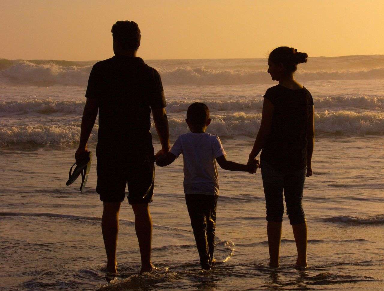 Una pareja en la playa con su hijo (Pixabay)